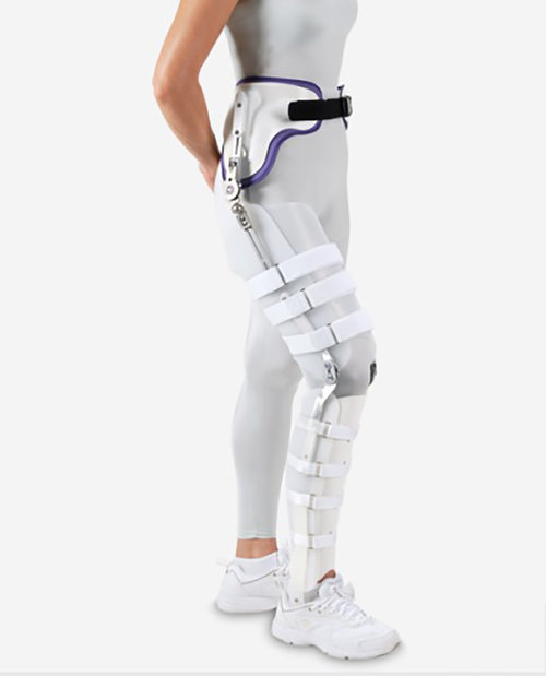A woman wearing a Hip Knee Ankle Foot Orthosis on her right leg